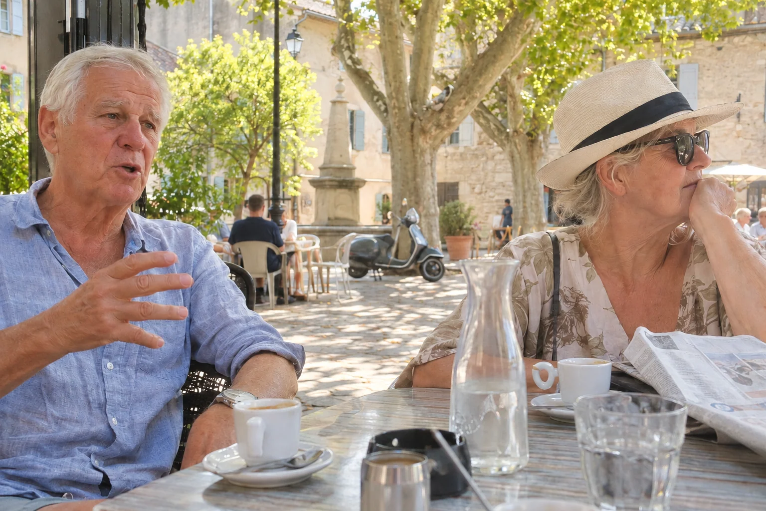 Et ældre par ved et cafébord med kaffe på en lille plads i en fransk landsby