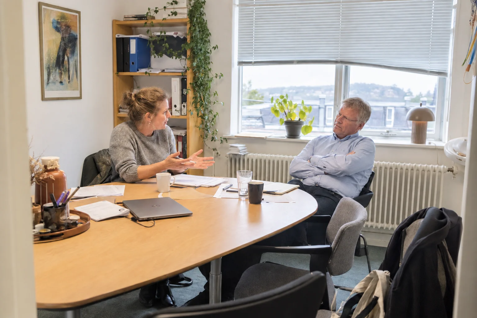 En rådgiver forklarer papirer til en lyttende kunde i et almindeligt mødelokale